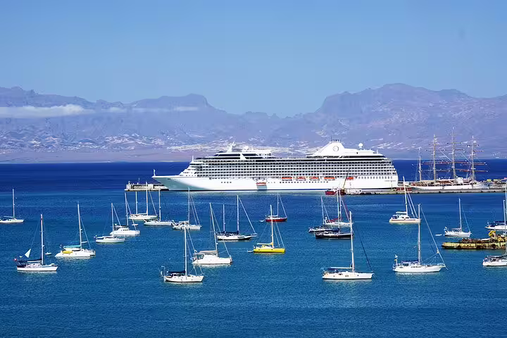 Cruise ship docked at Mindelo Port with sailboats in the foreground, offering scenic views for shore excursion travelers.