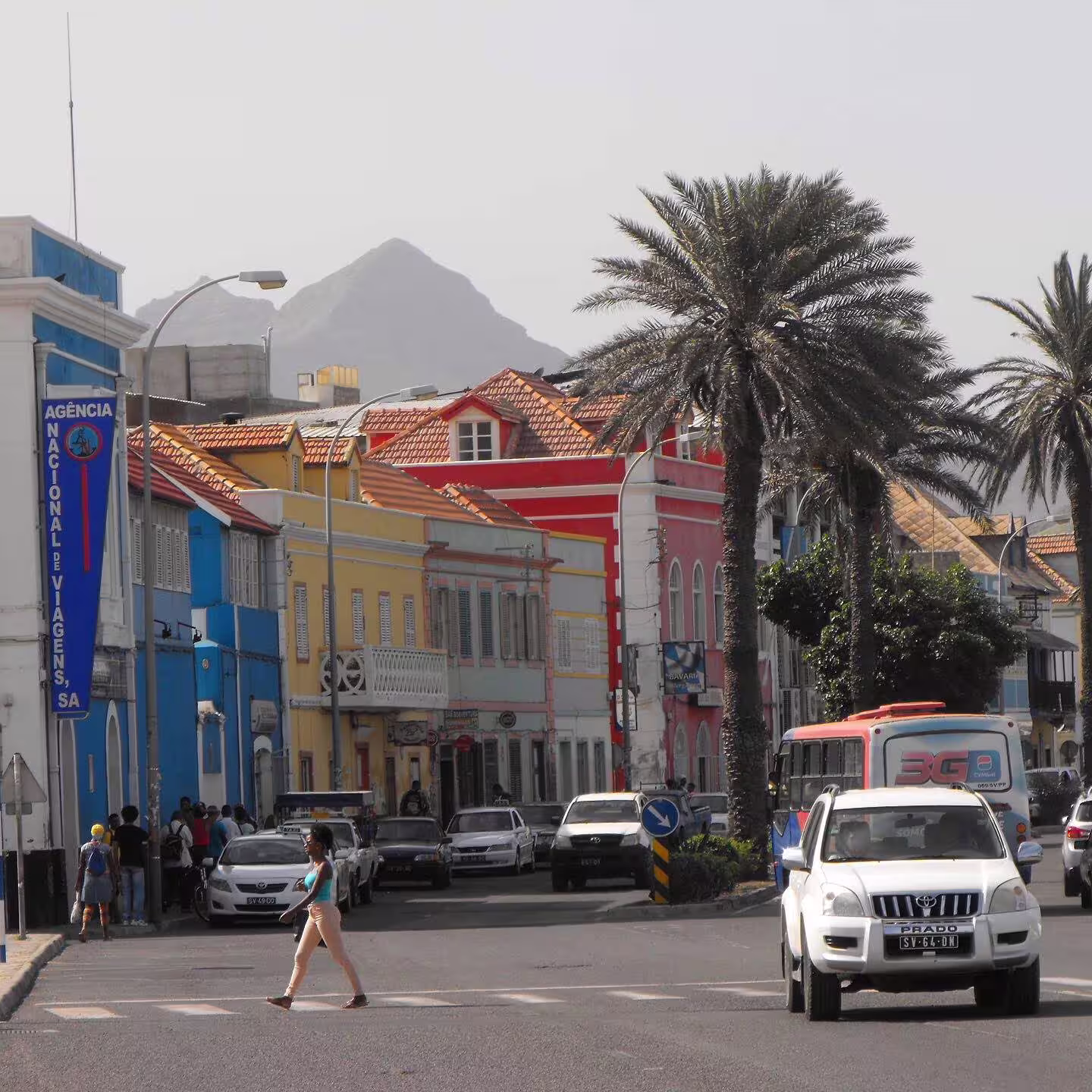 Colorful street view in Mindelo, São Vicente, featuring vibrant colonial architecture and palm trees under a clear sky.
