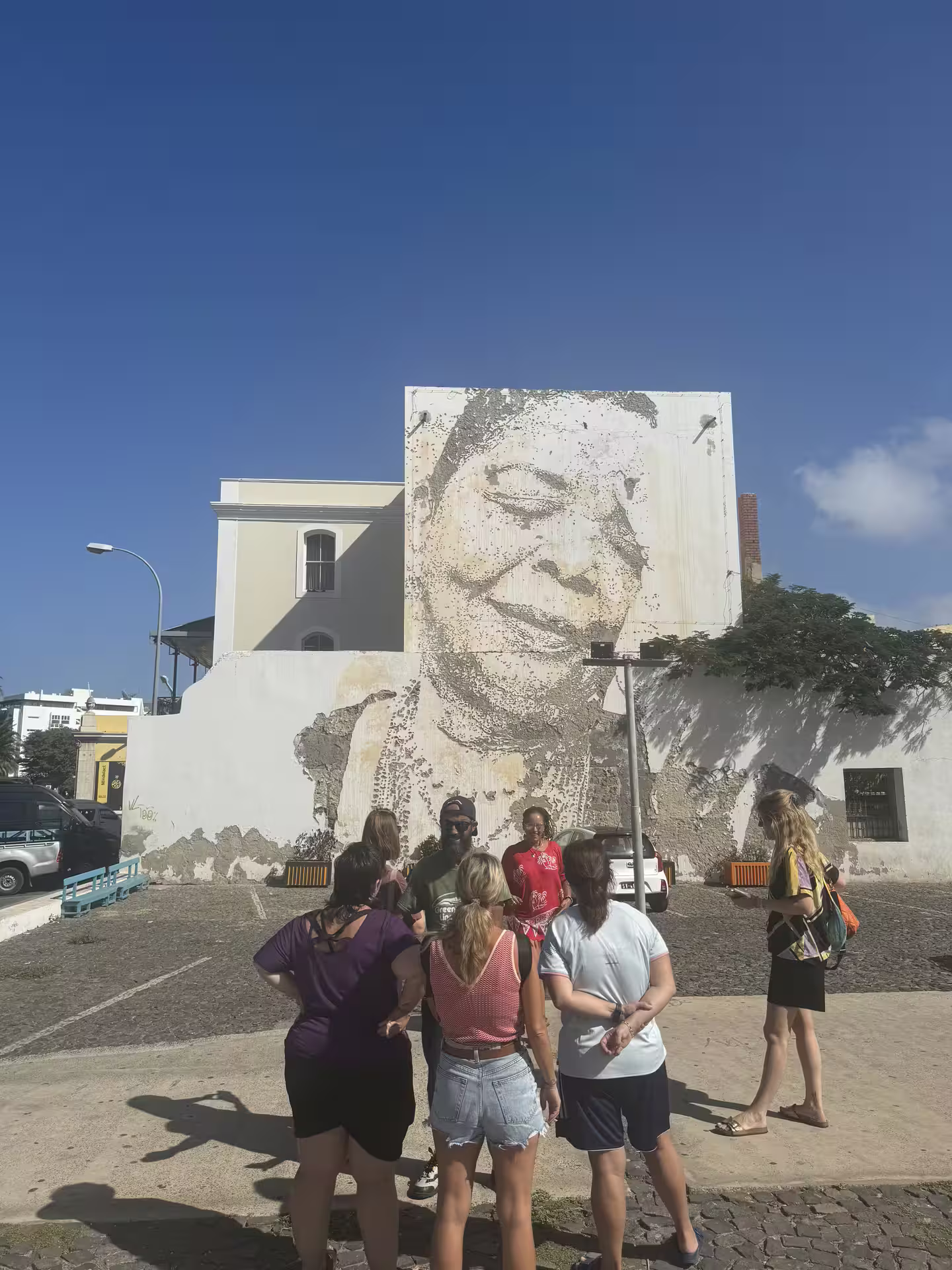 Tourists admire a large mural in Mindelo, São Vicente, during a guided island tour highlighting cultural and historical sites.