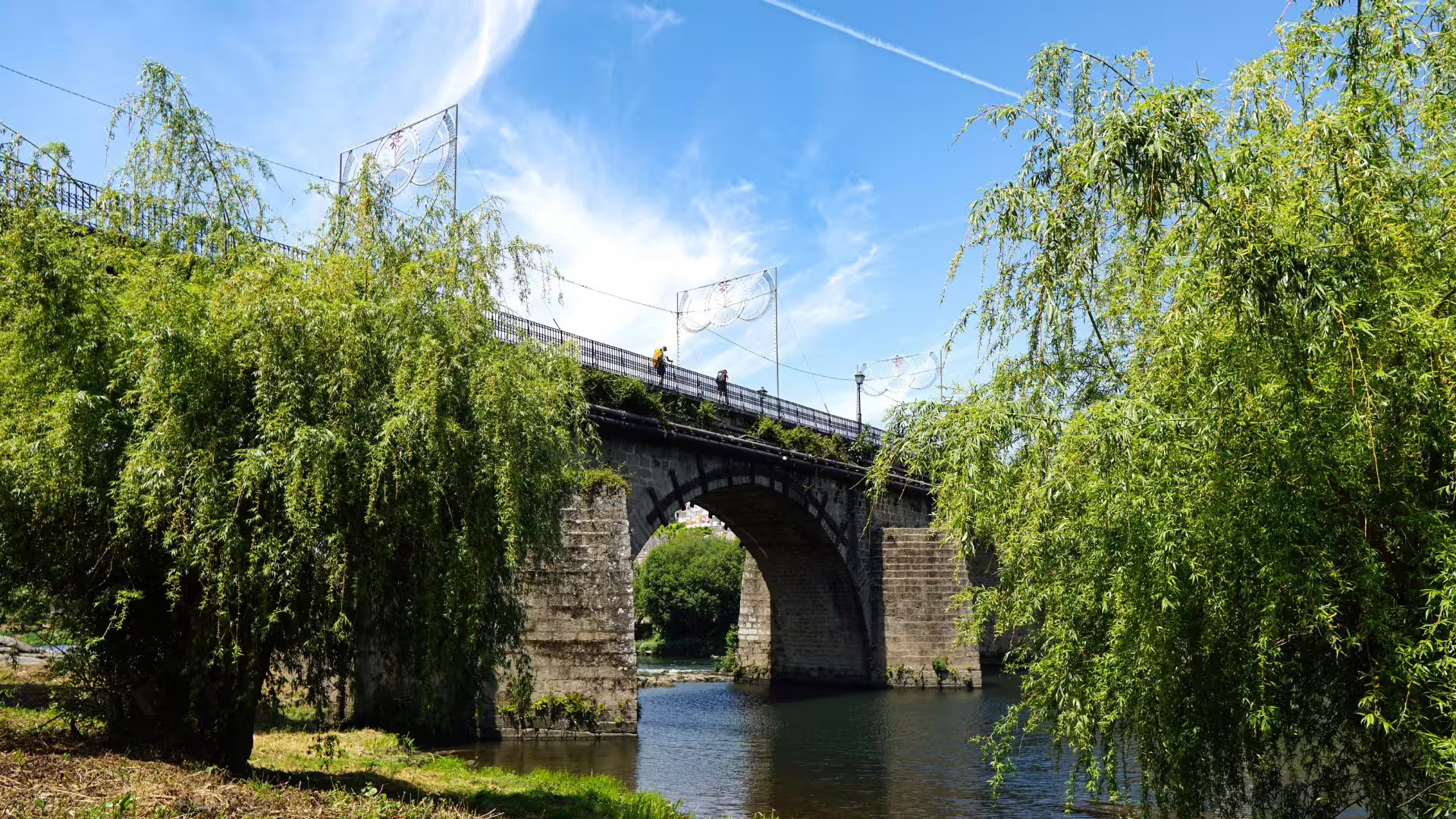 Scenic stone bridge over a tranquil river surrounded by lush greenery in the Minho region, perfect for nature tours.