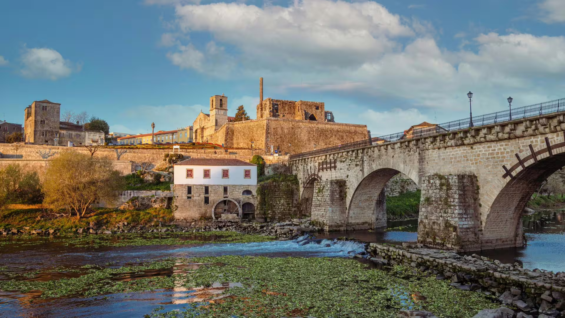 Historic stone bridge and ancient architecture overlooking a serene river in the picturesque Minho region.