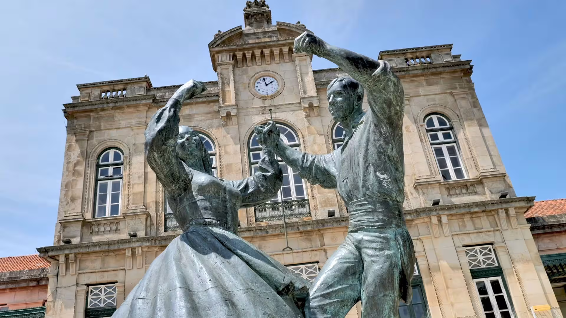 Historic statue of dancing couple in front of a classic building, Minho Region tour attraction.
