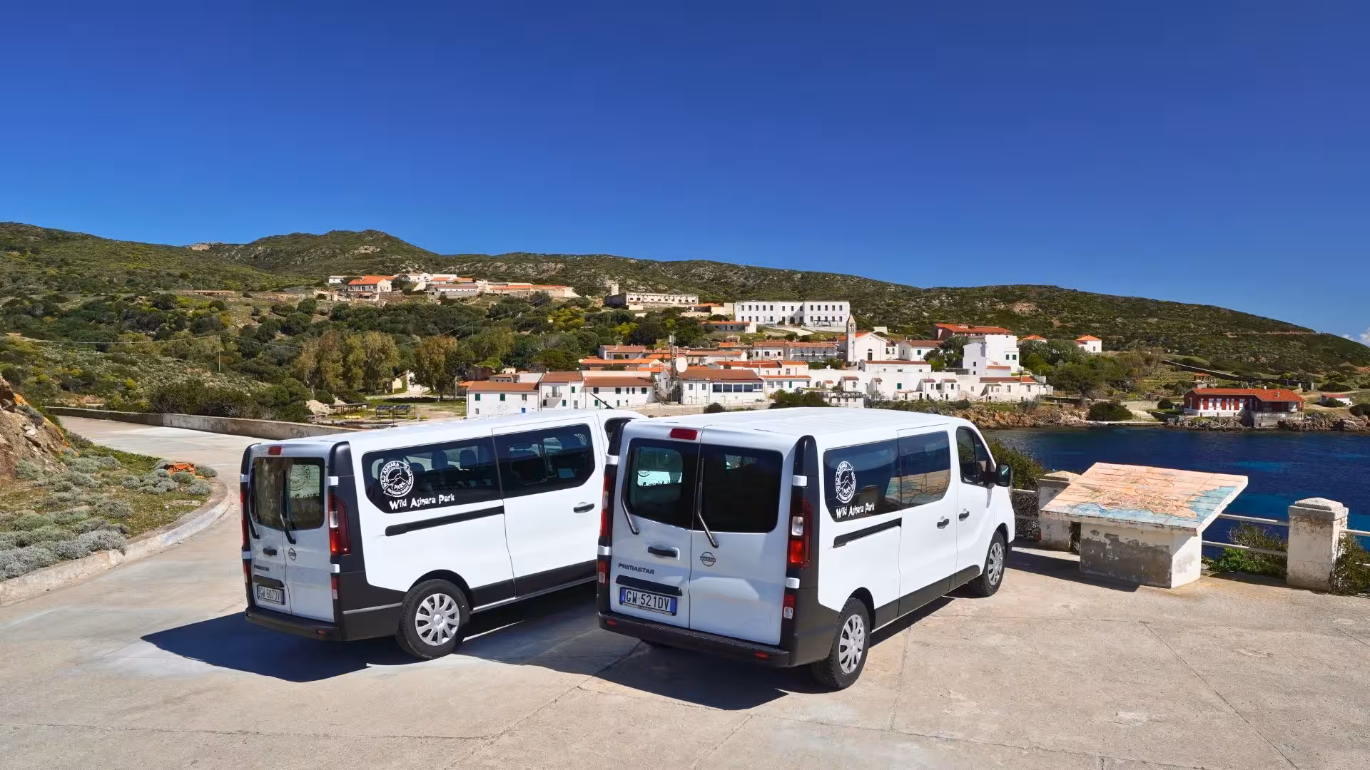 Two minivans parked overlooking Asinara village, ideal for exploring Sardinia's scenic landscapes and history.