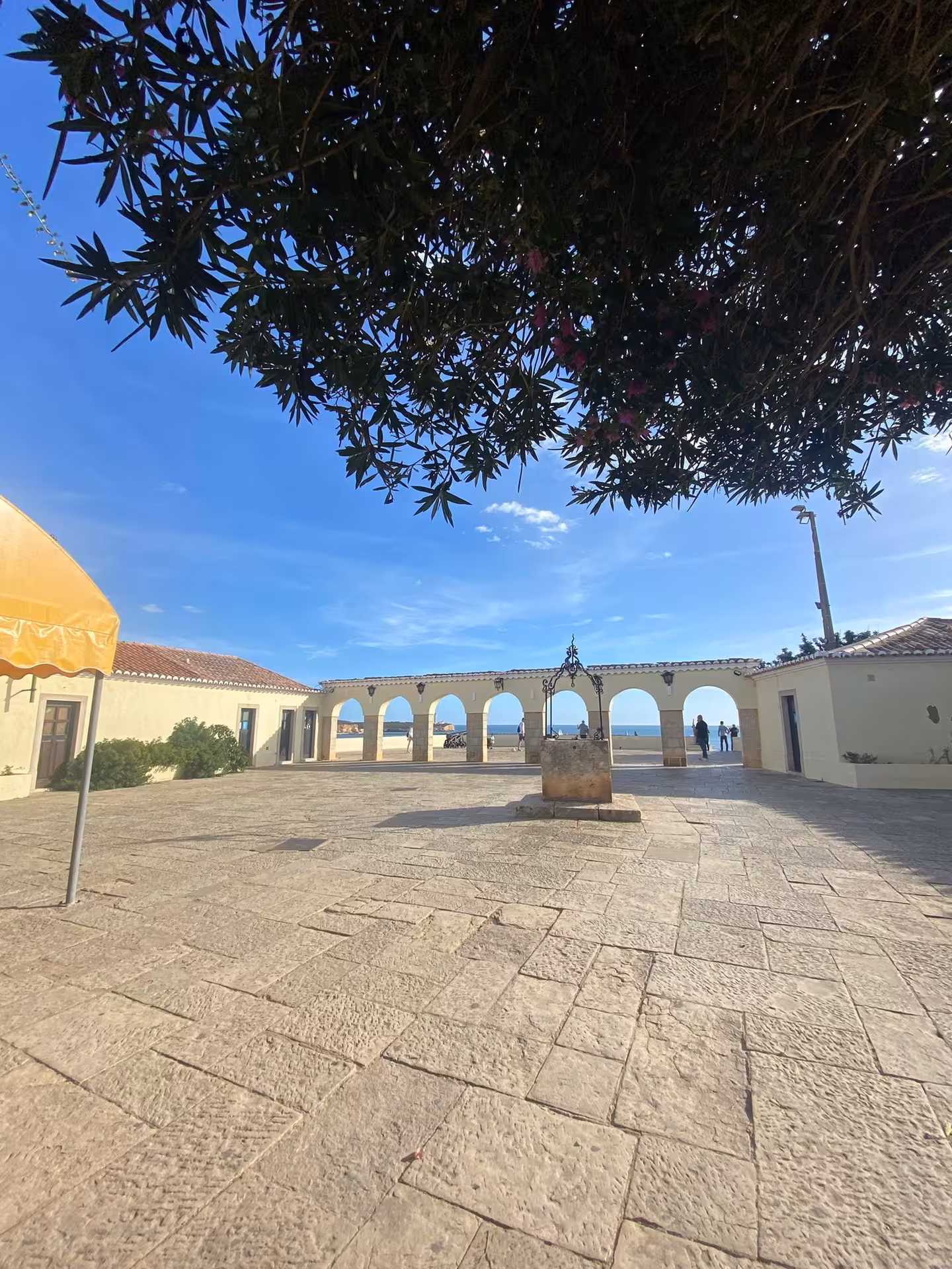 Sunny courtyard at Miradouro de Santa Catarina with arched colonnade framing Atlantic views between Arade River and Alvor Estuary