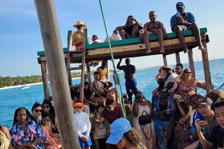 Tourists aboard a boat, soaking in the views on the Mnemba Island Dolphin & Snorkeling Tour, highlighting Zanzibar's natural beauty.