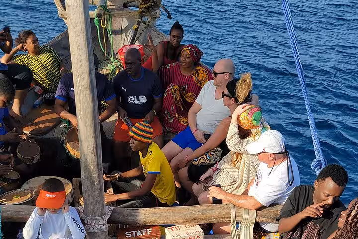 Group of tourists enjoying a traditional boat ride on the Mnemba Island Dolphin & Snorkeling Tour in Zanzibar.