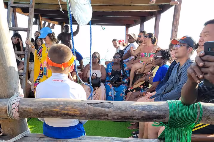 Tourists on a traditional dhow boat enjoying Mnemba Island Dolphin & Snorkeling Tour, a popular Zanzibar adventure activity.