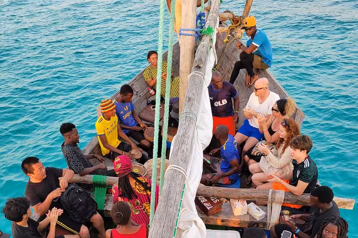 Tourists enjoying a vibrant dhow cruise on turquoise waters during the Mnemba Island Dolphin Tour in Zanzibar.