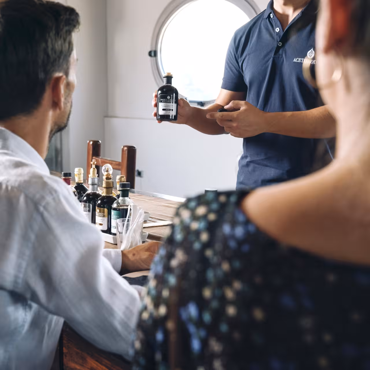 Acetaia host explains traditional balsamic vinegar of Modena tasting as guests sample Parmigiano and gelato