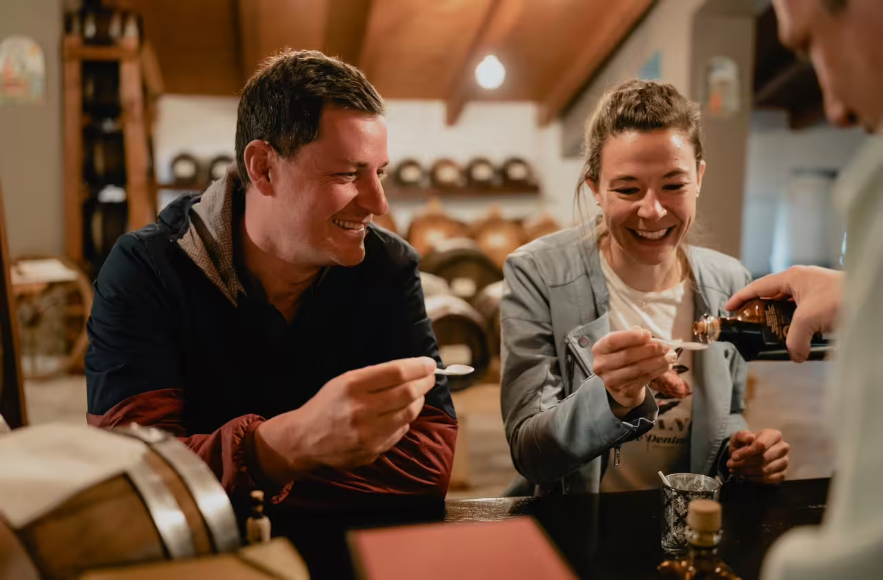 Two people enjoying a tasting of premium Balsamic Vinegar during a guided tour in Modena's renowned cellars.