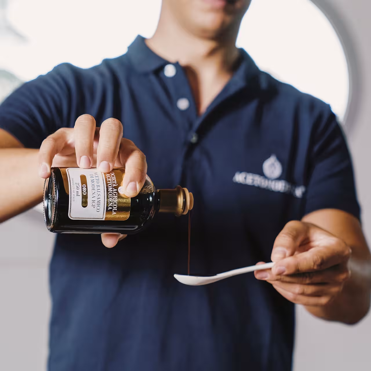 Guide pours Aceto Balsamico di Modena into tasting spoon on Modena balsamic vinegar tour experience