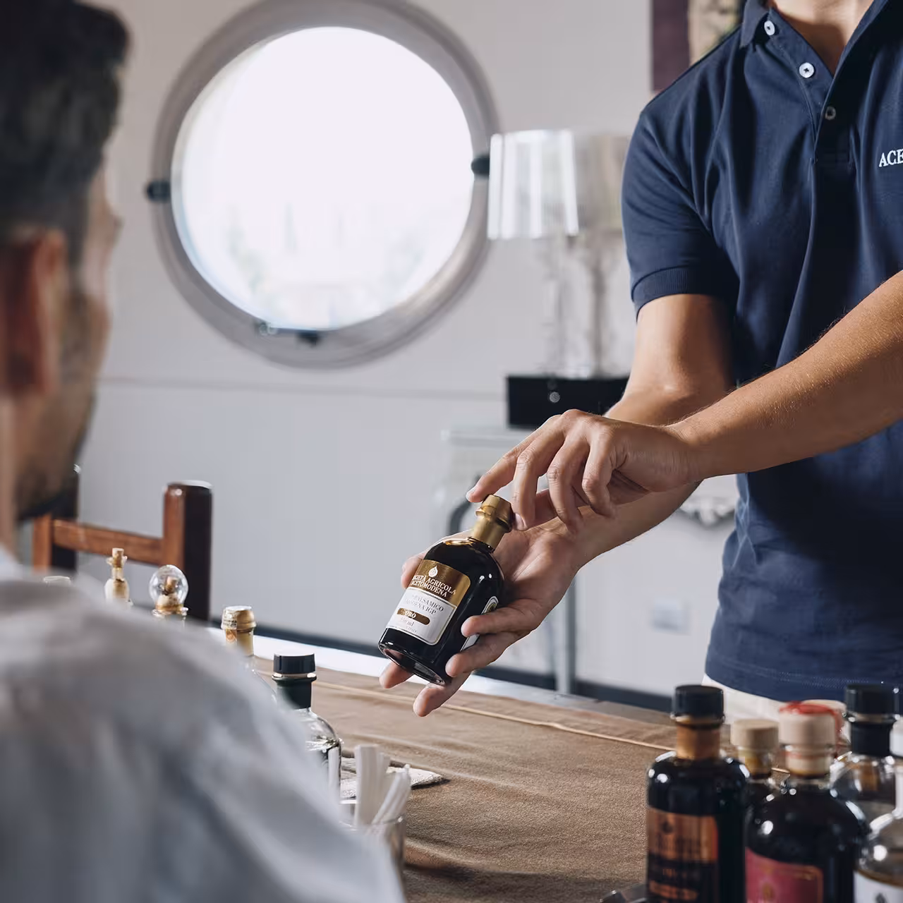 Guide presents a bottle during Modena balsamic vinegar tour tasting with Parmigiano Reggiano and gelato