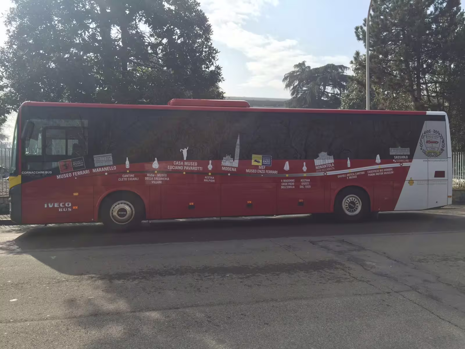 Red shuttle bus for Modena transfer to Ferrari Maranello and Enzo Ferrari Museum, parked roadside