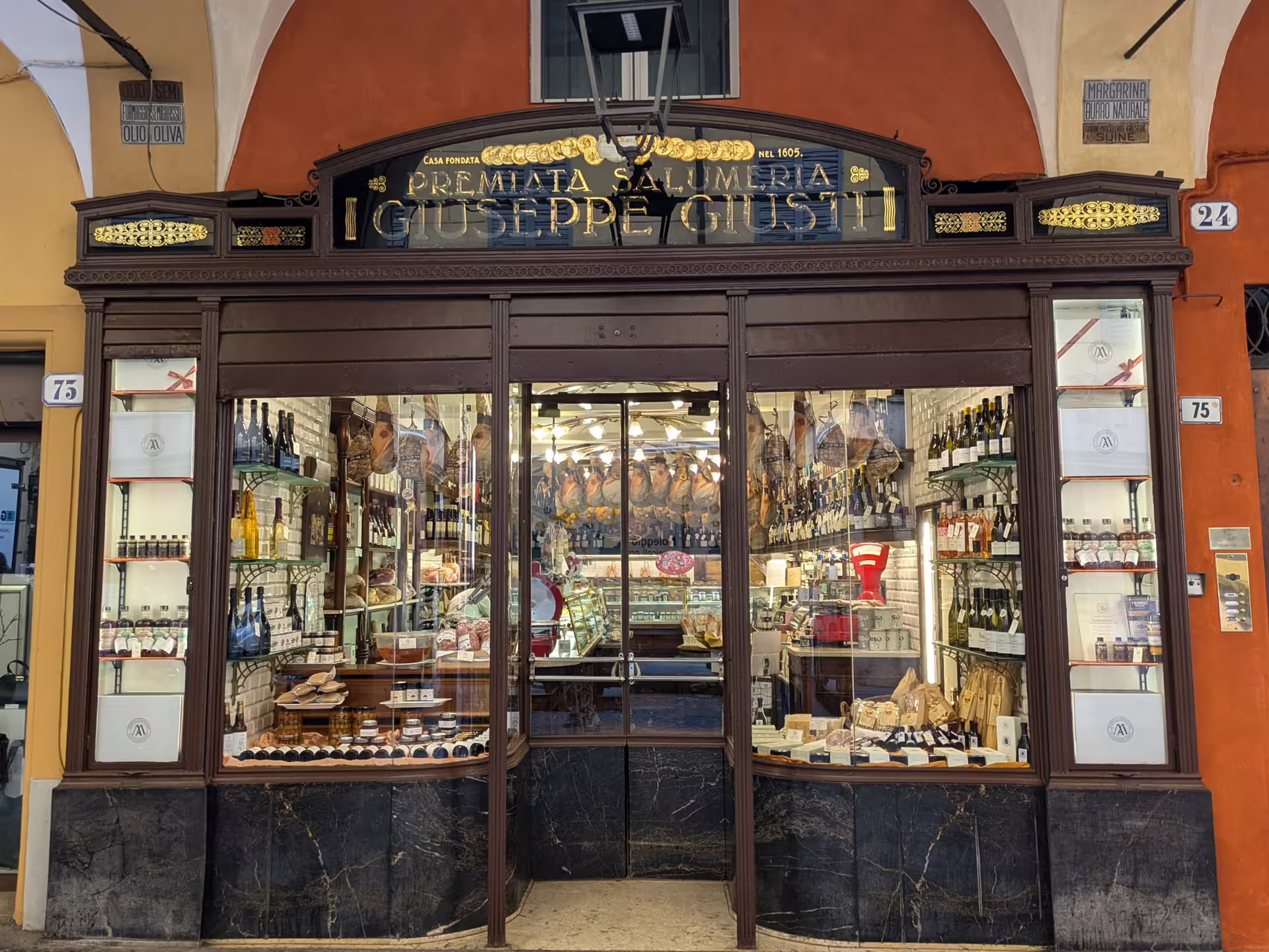 Charming storefront of a traditional Modena delicatessen showcasing fine Italian wines, meats, and gourmet delicacies.