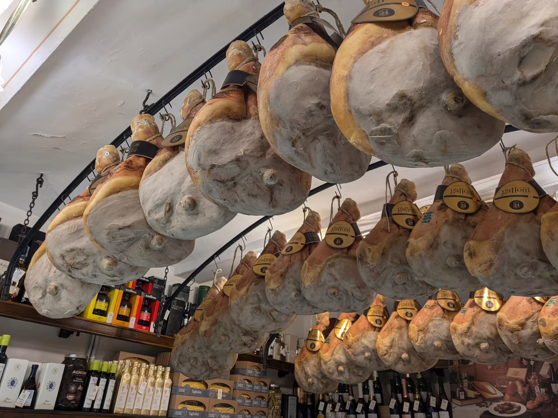 Authentic Italian prosciutto hanging in a Modena deli, a highlight of the local food tour experience.