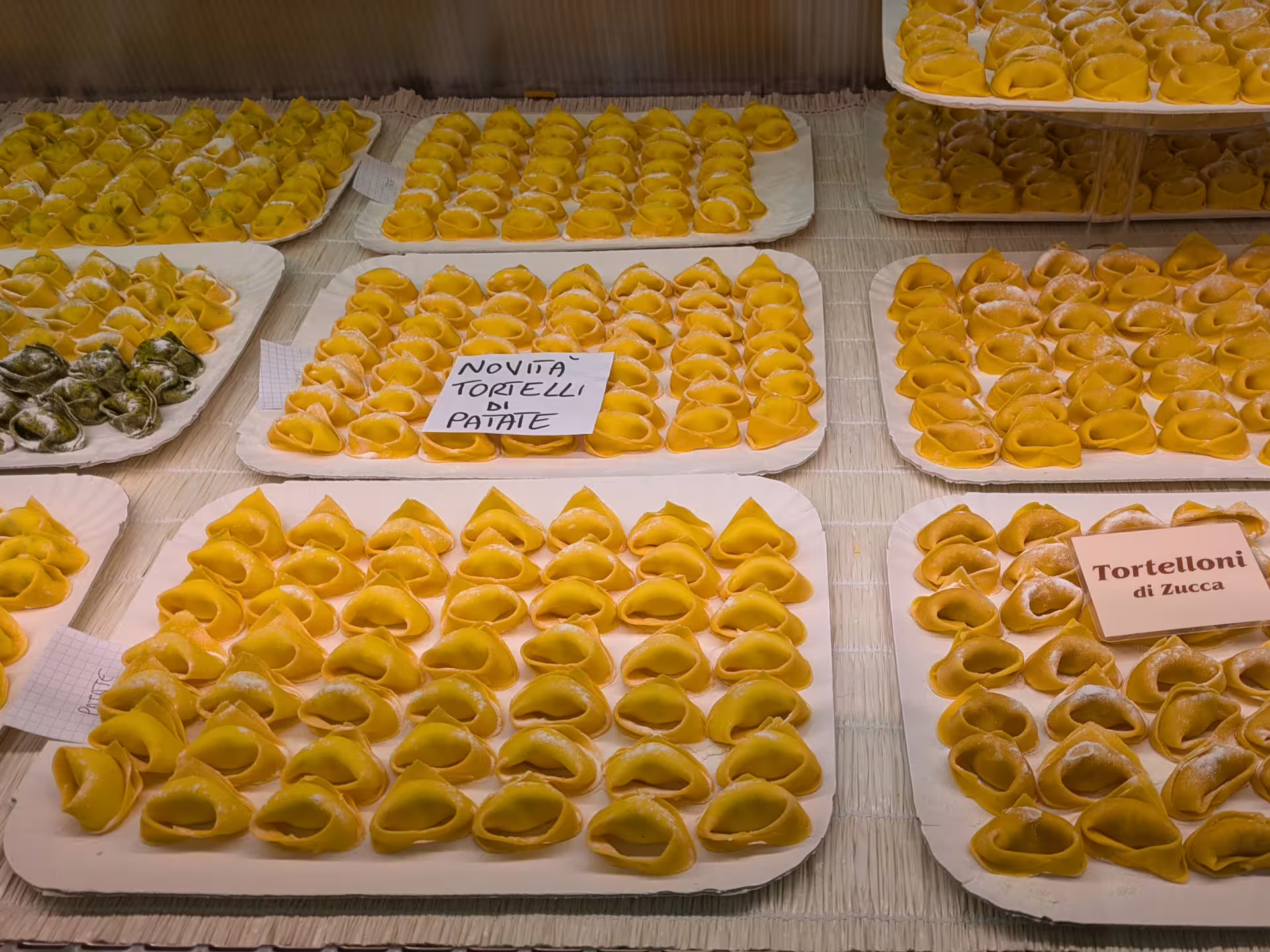 Display of handmade tortelloni varieties at Modena market, featuring pumpkin and potato fillings on the food tour.