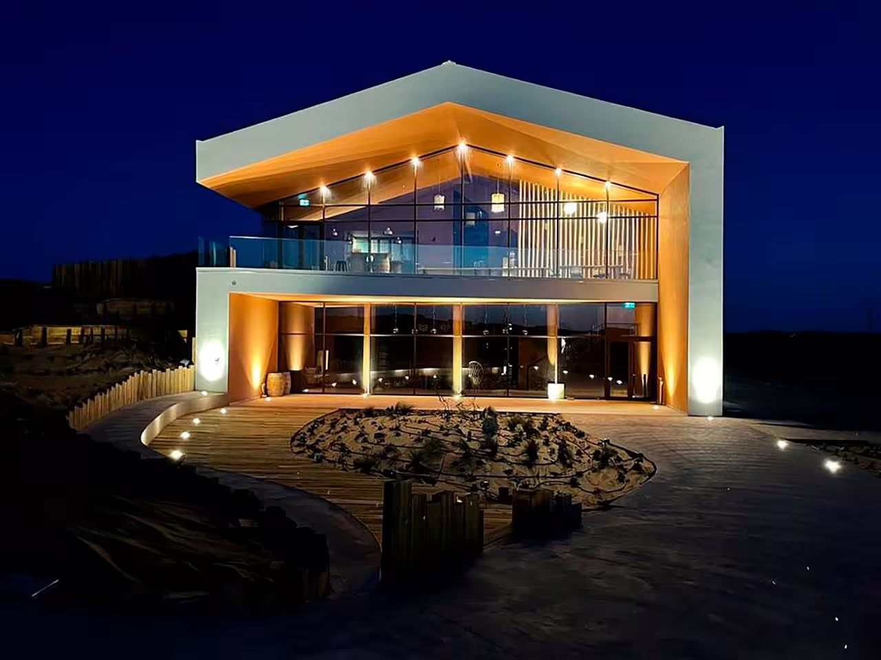 Modern winery illuminated at night, offering a scenic venue for a wine tasting experience featuring six exquisite wines.