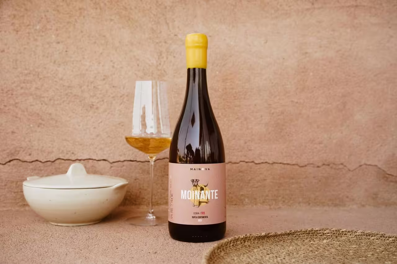 Bottle of Moinante wine with a glass against a rustic backdrop, perfect for a wine tasting tour experience.