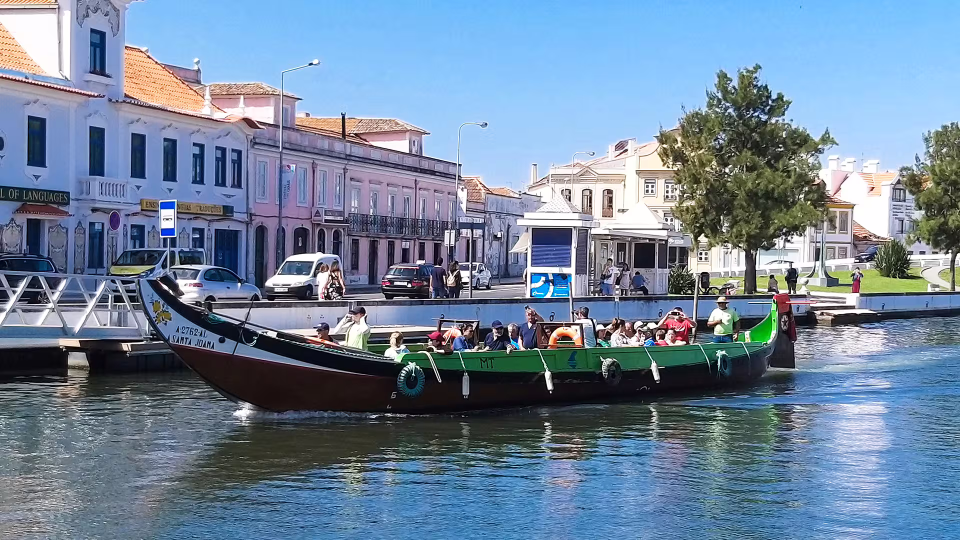Traditional moliceiro boat tour on Aveiro canal showcasing colorful architecture and vibrant Costa Nova striped houses.