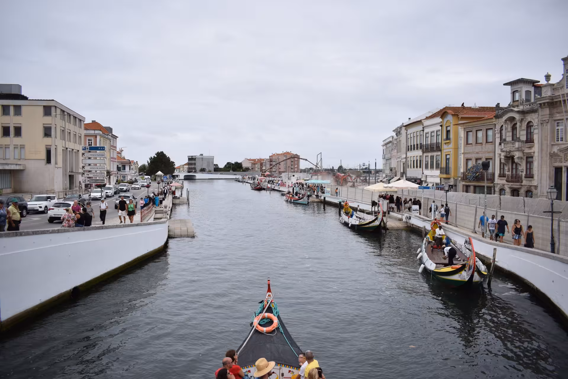 Moliceiro boat cruising Aveiro canals on a private half-day tour, with waterfront buildings and crowds