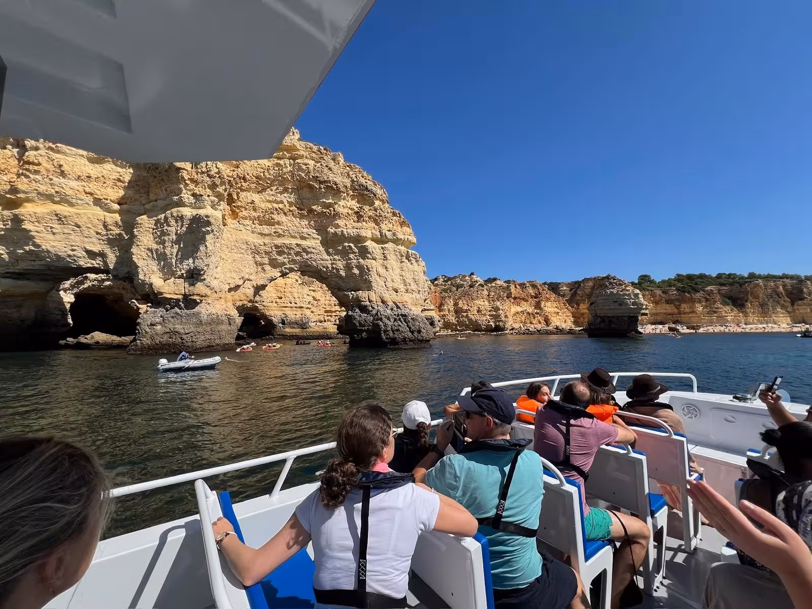 Passengers enjoying scenic views of coastal cliffs on Moments Caves & Coastline tour boat.