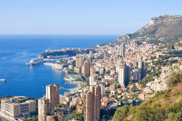Panoramic view of Monaco's coastline and cityscape with luxurious yachts and Mediterranean Sea vistas.