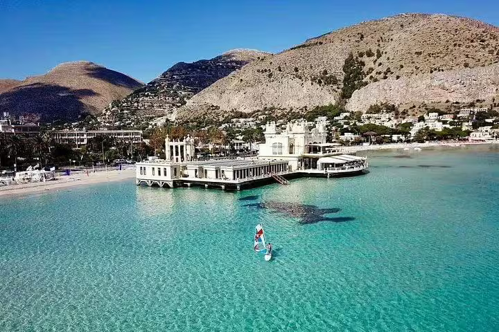 Crystal-clear turquoise sea and historic pier at Mondello Beach with Monte Pellegrino backdrop on Palermo full day tour