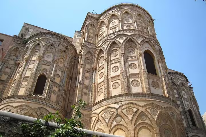 Detail of Monreale Cathedral’s ornate Norman-Arab arches and mosaics under a clear blue sky on a private tour from Palermo
