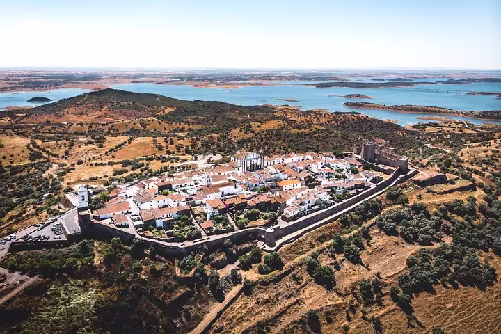 Aerial view of Monsaraz village, surrounded by medieval walls and scenic Alentejo landscape, featured in the Evora tour.