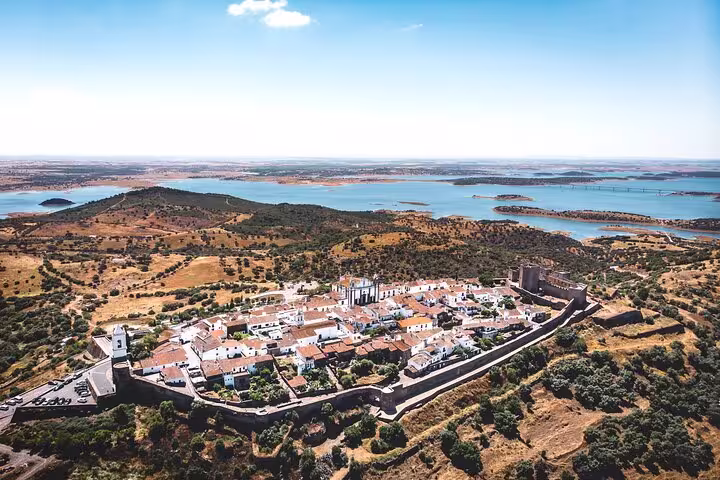 Aerial view of the historic Monsaraz village with Alqueva Lake backdrop, featured in the Évora & Monsaraz small-group tour from Lisbon.