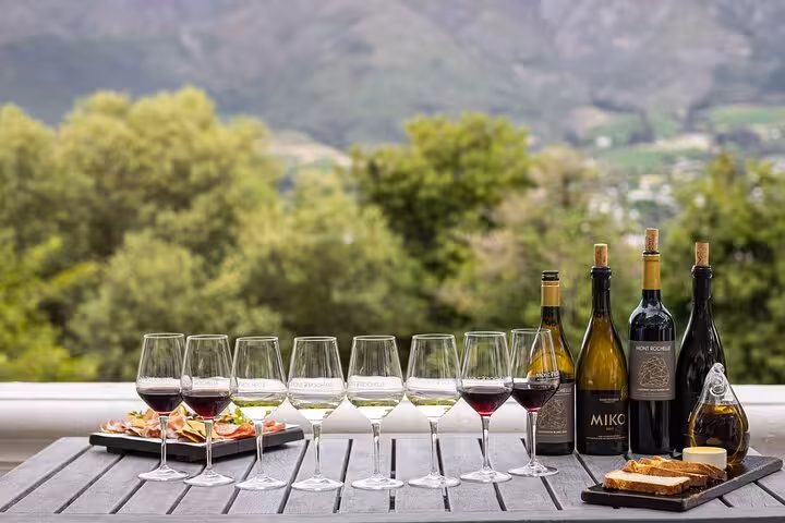 Wine tasting setup with Mont Rochelle wines and snacks, offering scenic vineyard views on Cape Town day tour.