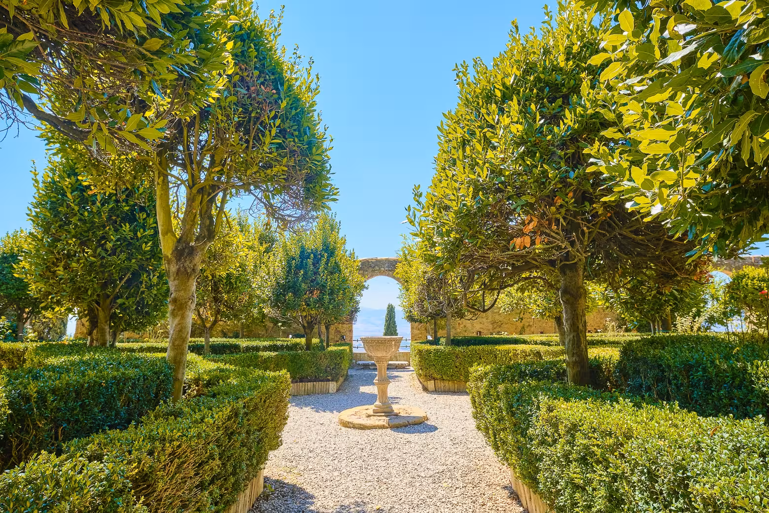 Explore the lush gardens of Montalcino on a private Val d'Orcia tour from Florence, featuring manicured hedges and arches.