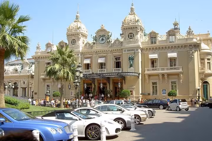 Elegant facade of Monte Carlo Casino with luxury cars parked in front, highlighting the allure of the French Riviera.