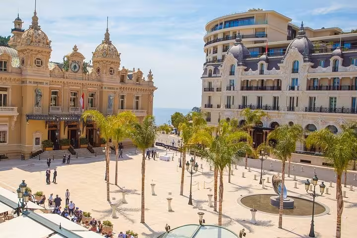 Elegant Monte Carlo Casino square in Monaco, surrounded by palm trees and grand historic buildings.