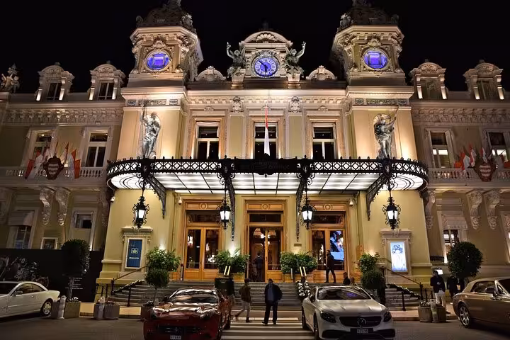 Elegant Monte Carlo Casino entrance lit up at night, a highlight of the Monaco private tour experience.