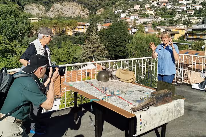 A woman enthusiastically explaining a historical map of Monte Cassino as photographers capture the moment.
