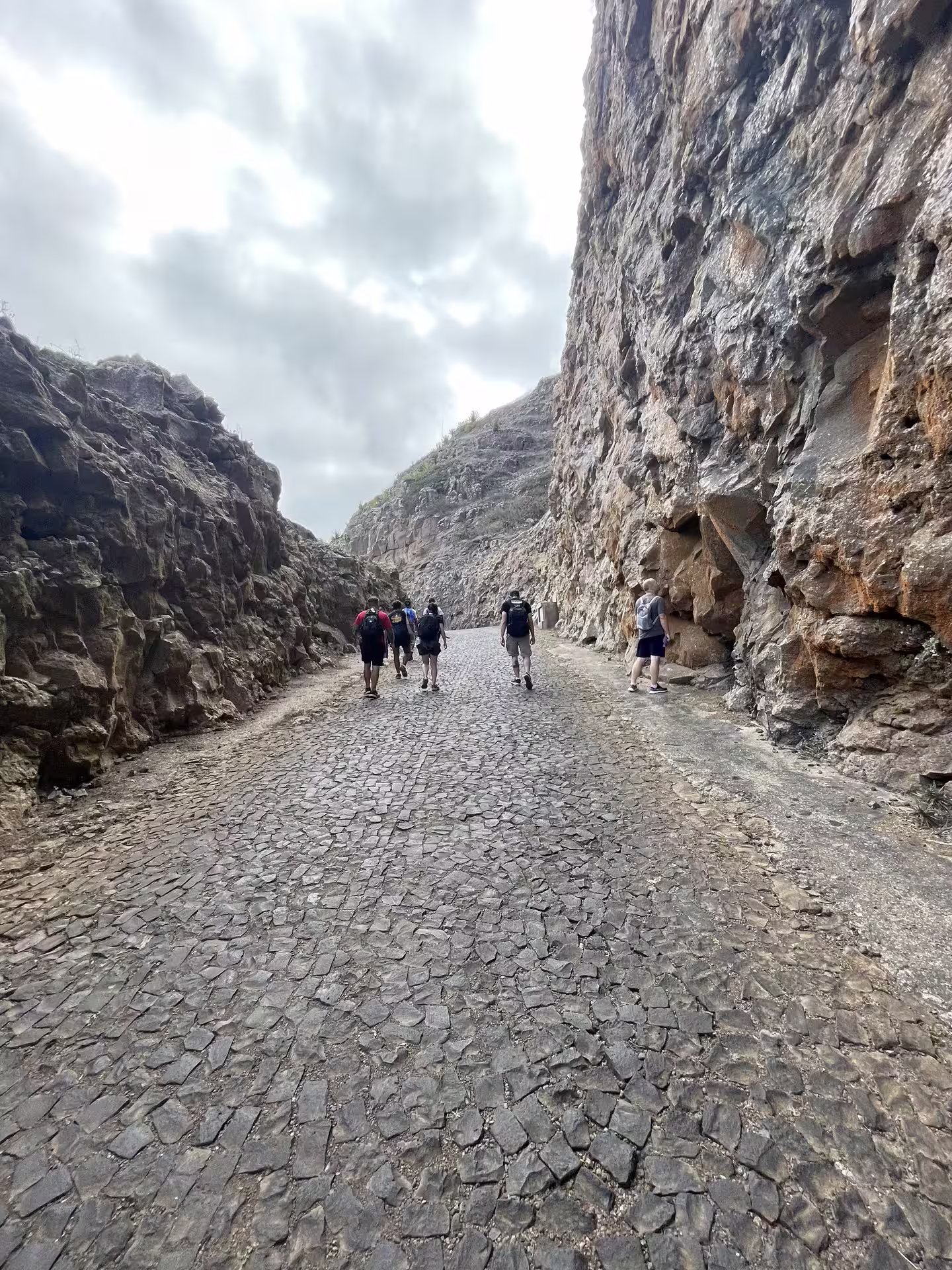 Hikers explore the scenic cobblestone path through rocky cliffs on the Monte Verde trail in São Vicente, Cape Verde.