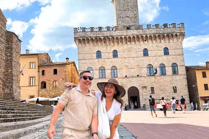 Happy tourists exploring the historic Piazza Grande in Montepulciano on a sunny day during a small group tour.