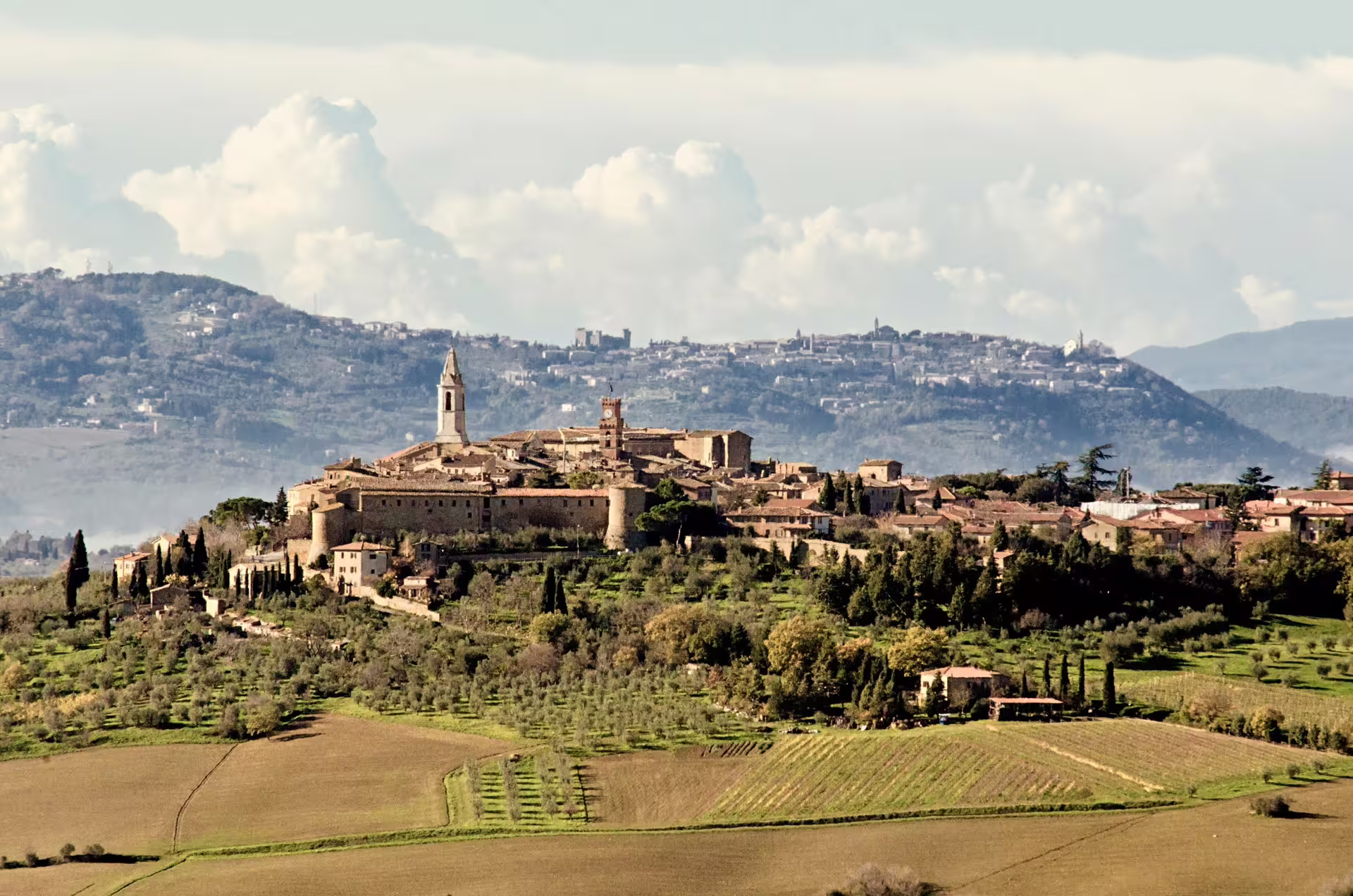 Medieval hilltop town of Montepulciano surrounded by vineyards and olive groves on a Tuscany flavors road trip