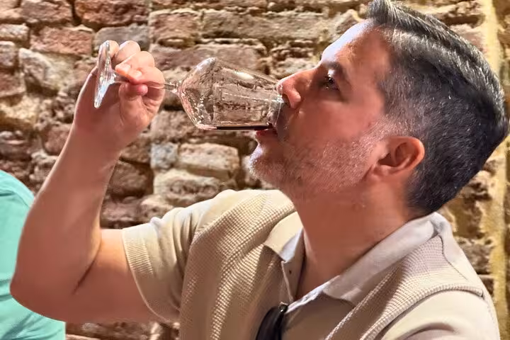 A guest savoring a glass of fine wine inside a rustic Montepulciano winery on a small group tour.