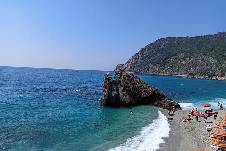 Turquoise waves and sunbathers along Monterosso al Mare beach in Cinque Terre, Italy, on a private wonderland day tour