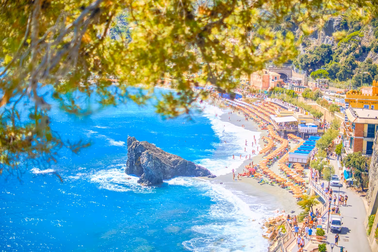 Vibrant beach scene in Monterosso al Mare, part of the Cinque Terre tour from Florence, with colorful umbrellas and clear waters.