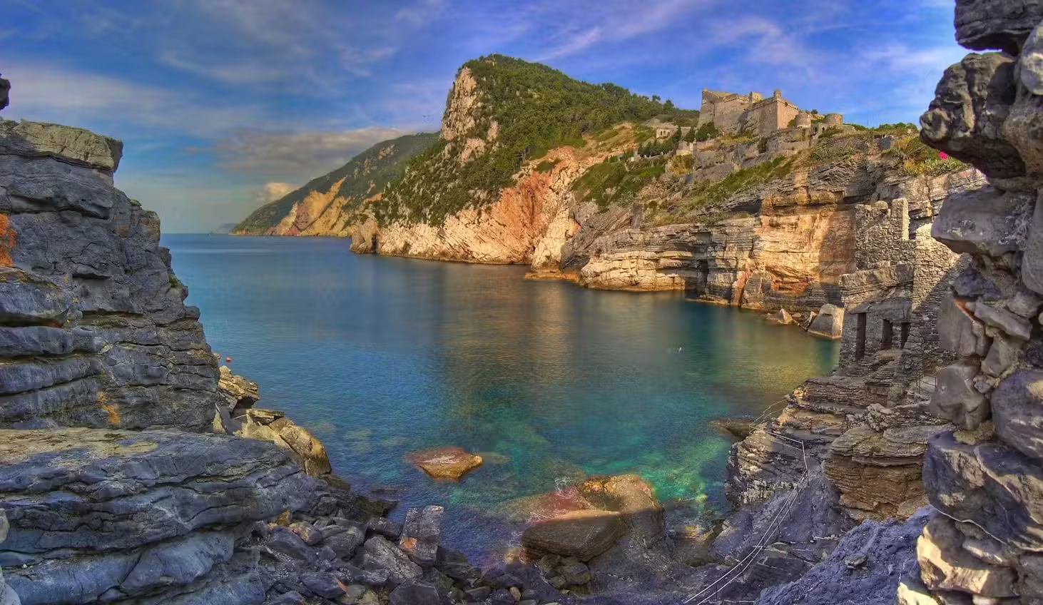Rocky cove and medieval ruins near Monterosso showcasing clear turquoise Ligurian waters on a Cinque Terre tour