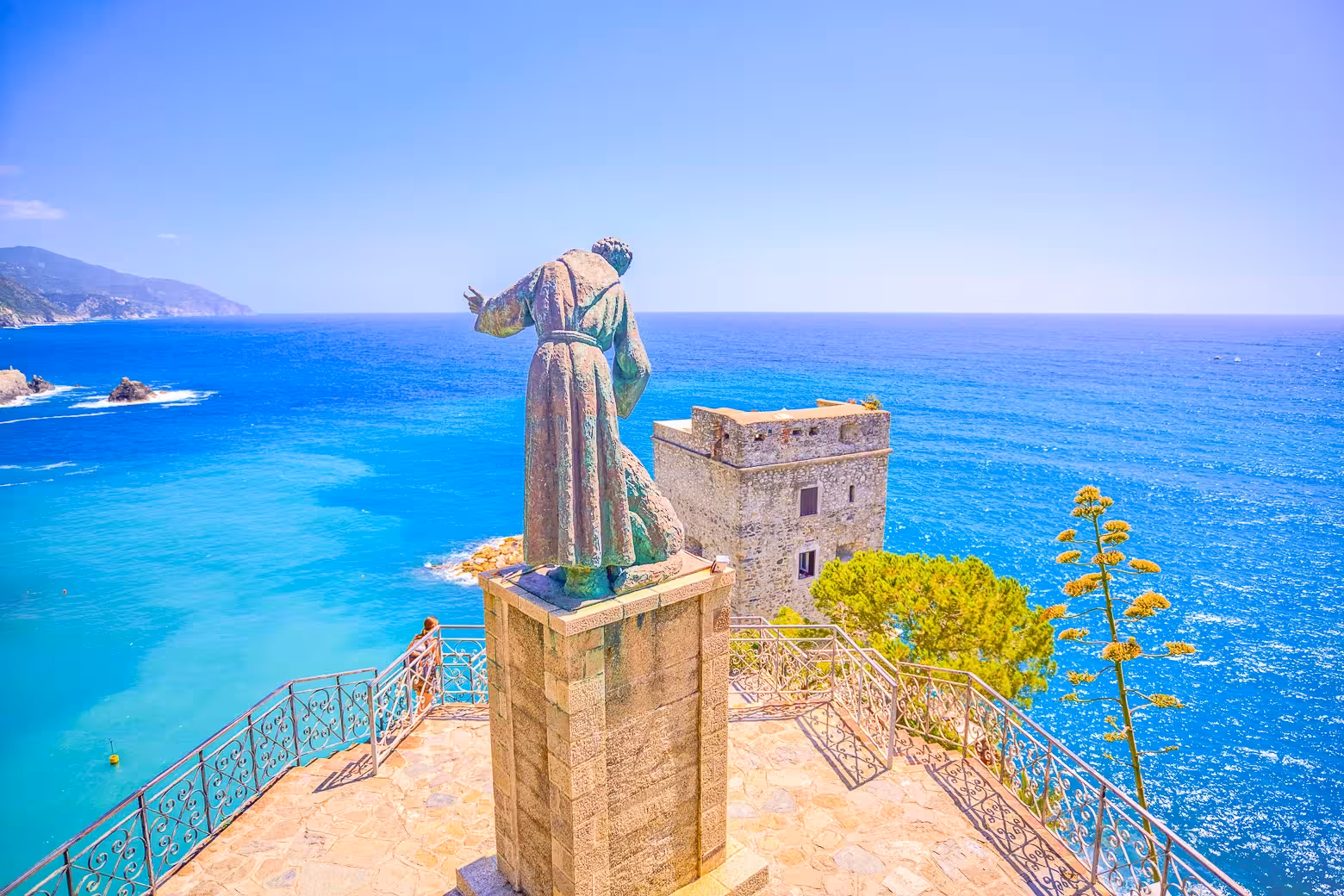 Stunning view of the Monterosso coastline with a historic statue overlooking the azure Ligurian Sea, Cinque Terre tour.