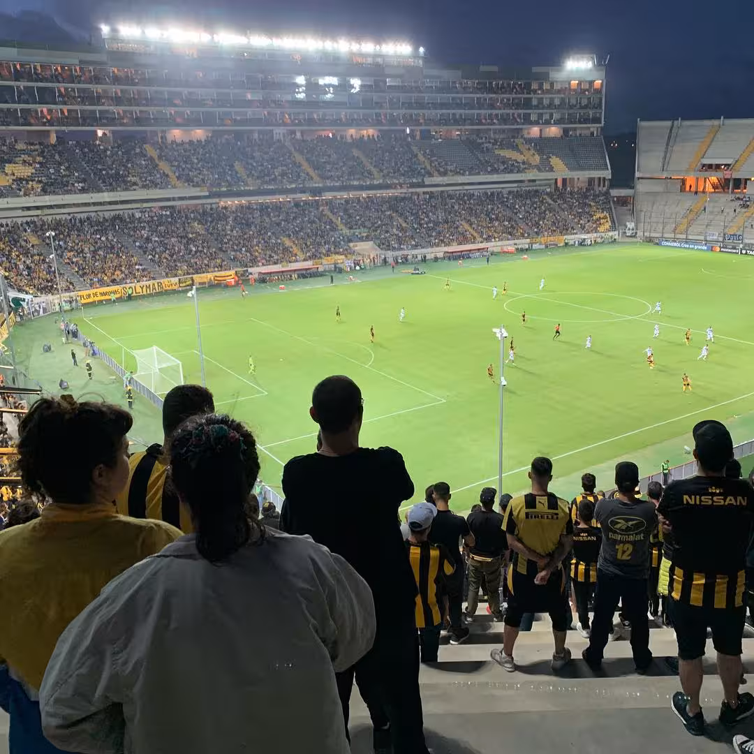Night view of a Montevideo football match from the stands, Peñarol fans watching on a local matchday experience