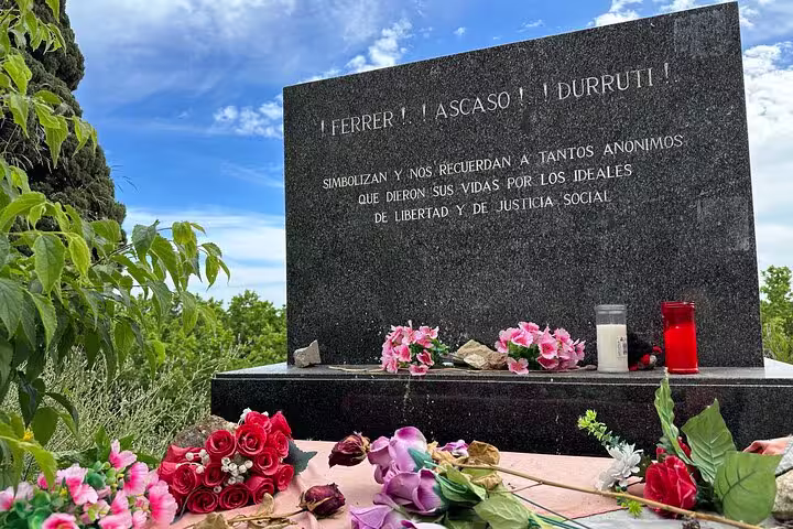 Floral tributes adorn a monument at Montjuïc Cemetery, commemorating history and ideals on the Hidden Art & Views tour.