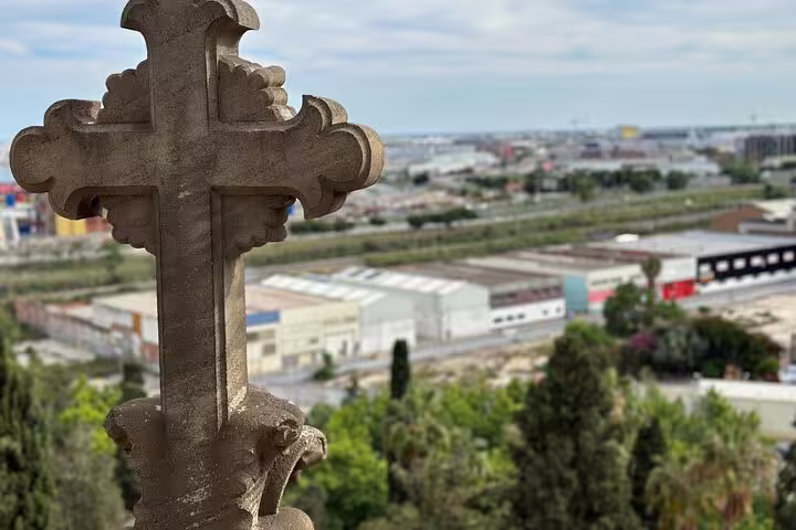 Discover the panoramic cityscape views from Montjuïc Cemetery, highlighted by its iconic stone cross and lush greenery.