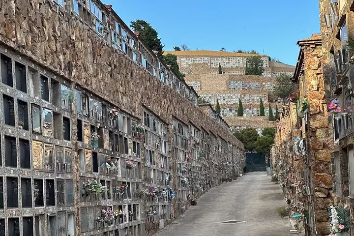 Explore the historic Montjuïc Cemetery with intricate stone niches and scenic hillside views on this guided walking tour.