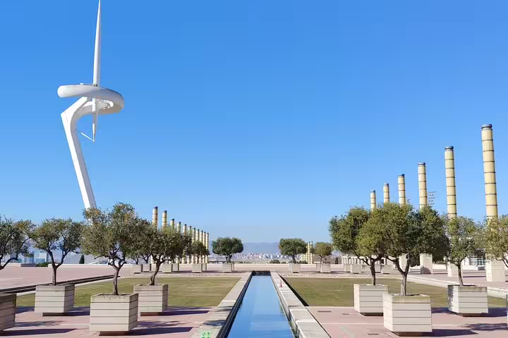 Montjuïc Communications Tower and landscaped gardens under a clear blue sky in Barcelona's Montjuic area.