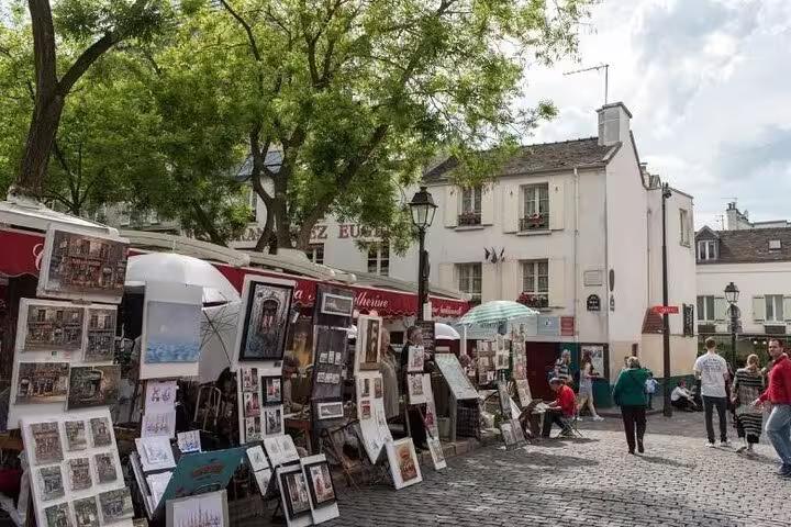 Hand holding a smartphone displaying a GPS walking tour app in Montmartre with Sacré-Cœur Basilica in the background.